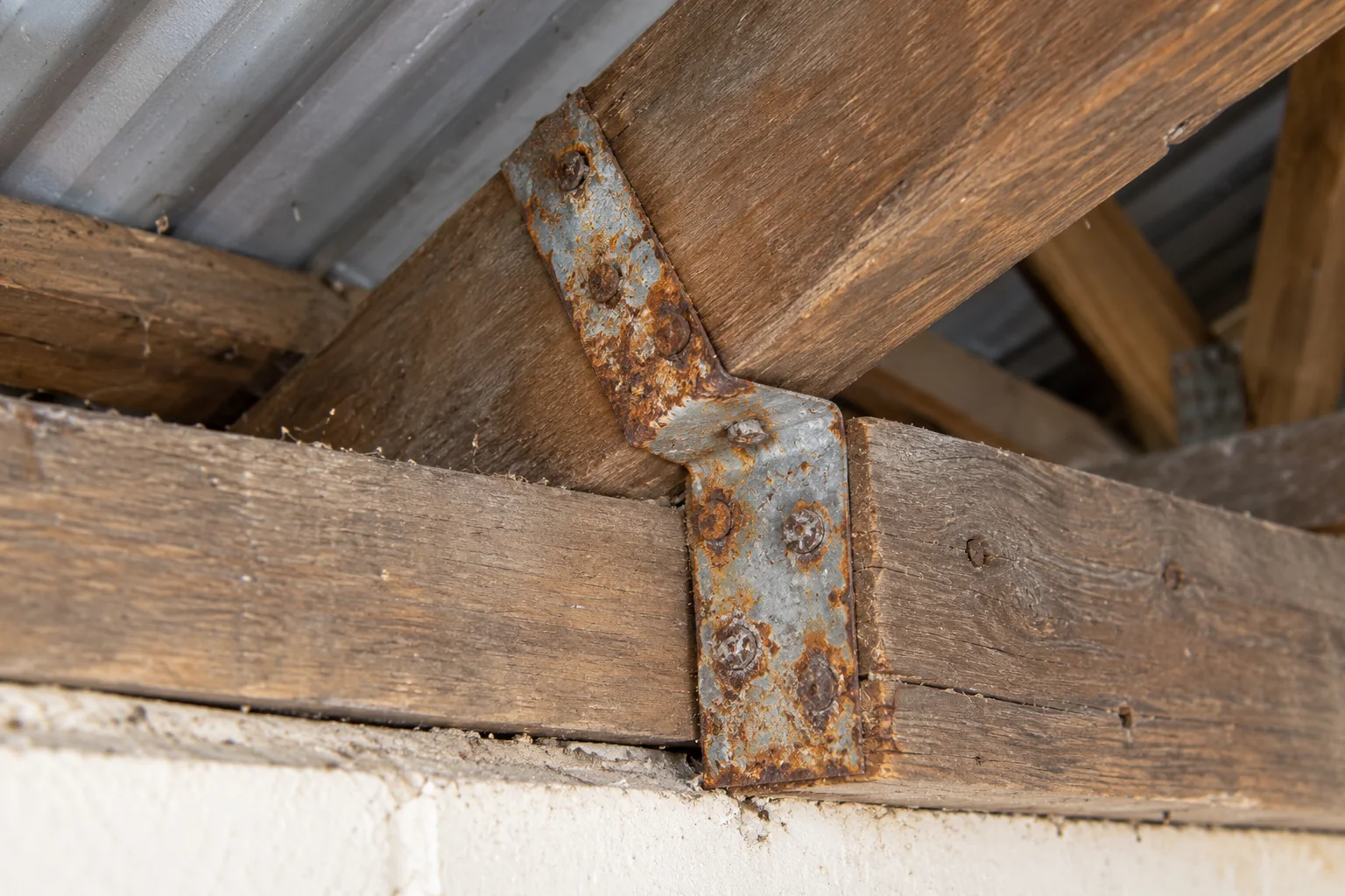 Rusty strap where a rafter meets the wall